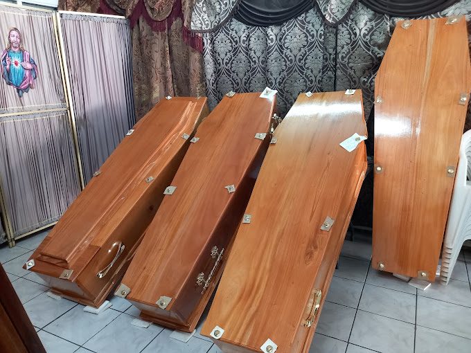 Quatre cercueils en bois verni présentés dans la salle d'exposition