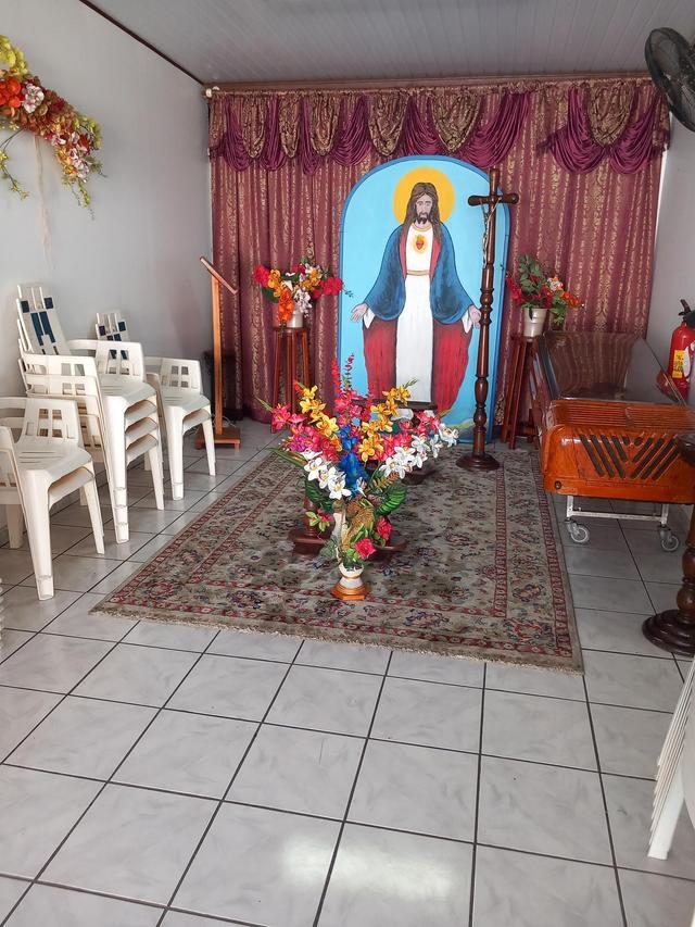 Salle de veillée avec chaises, fleurs, tapis et rideaux, prête pour le recueillement